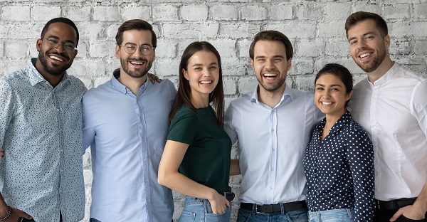 Happy diverse young people teammates hugging and looking at camera